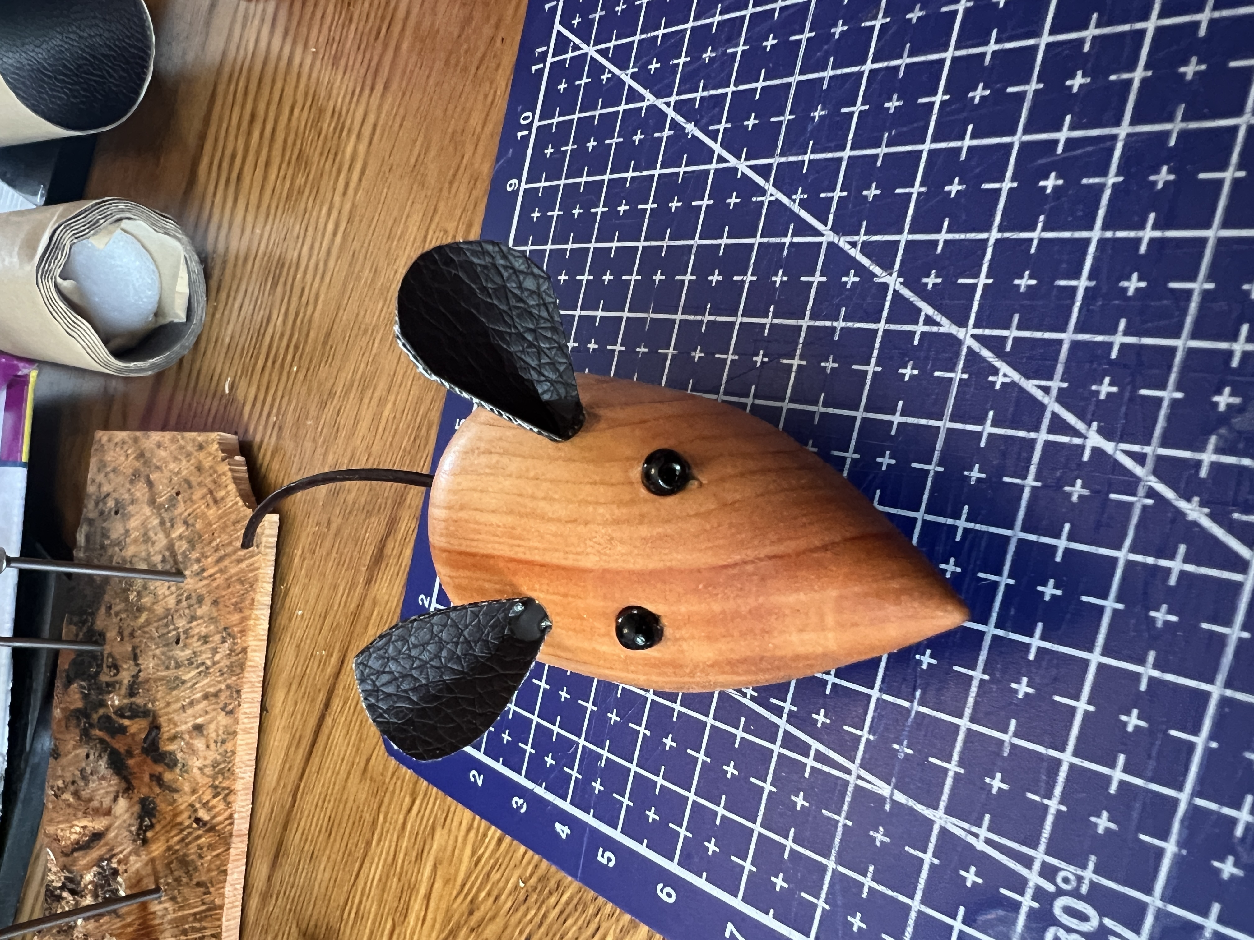 A finished turned wooden mouse with a leather tail, bead eyes and pleather ears